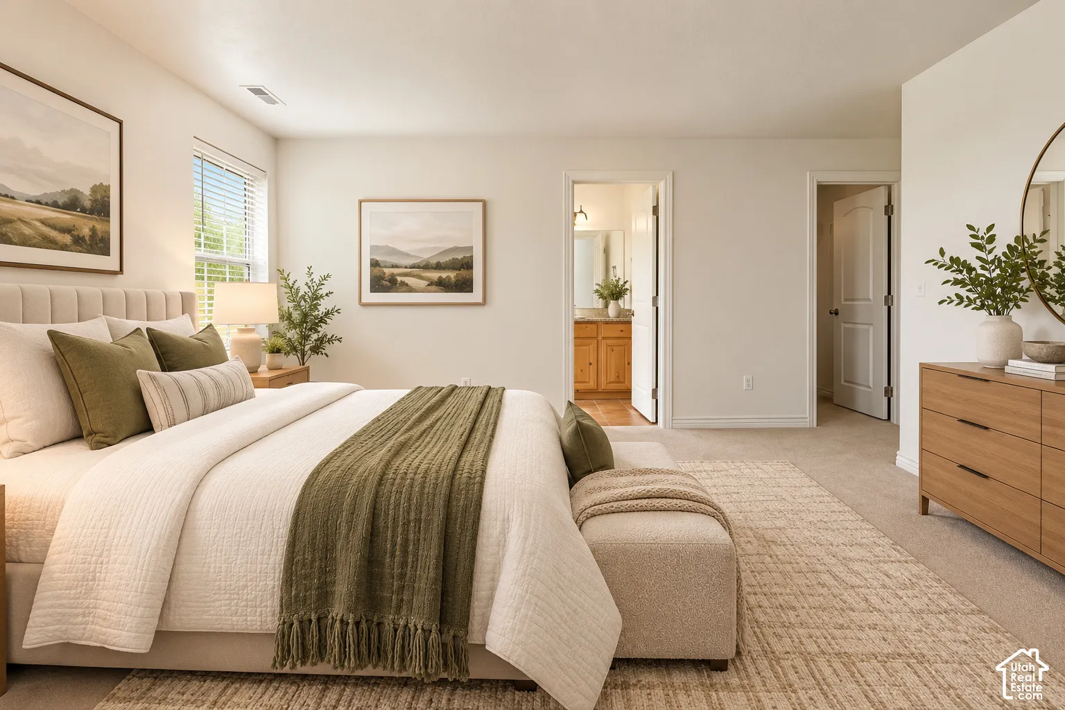 Carpeted bedroom featuring a large window with blinds and access to a bathroom with wood cabinetry- VIRTUALLY STAGED
