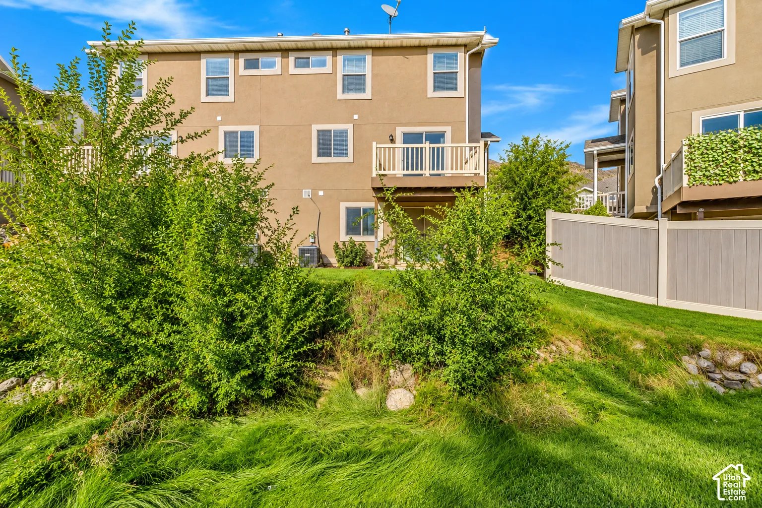 Multi-story stucco exterior featuring multiple windows and a white balustrade deck