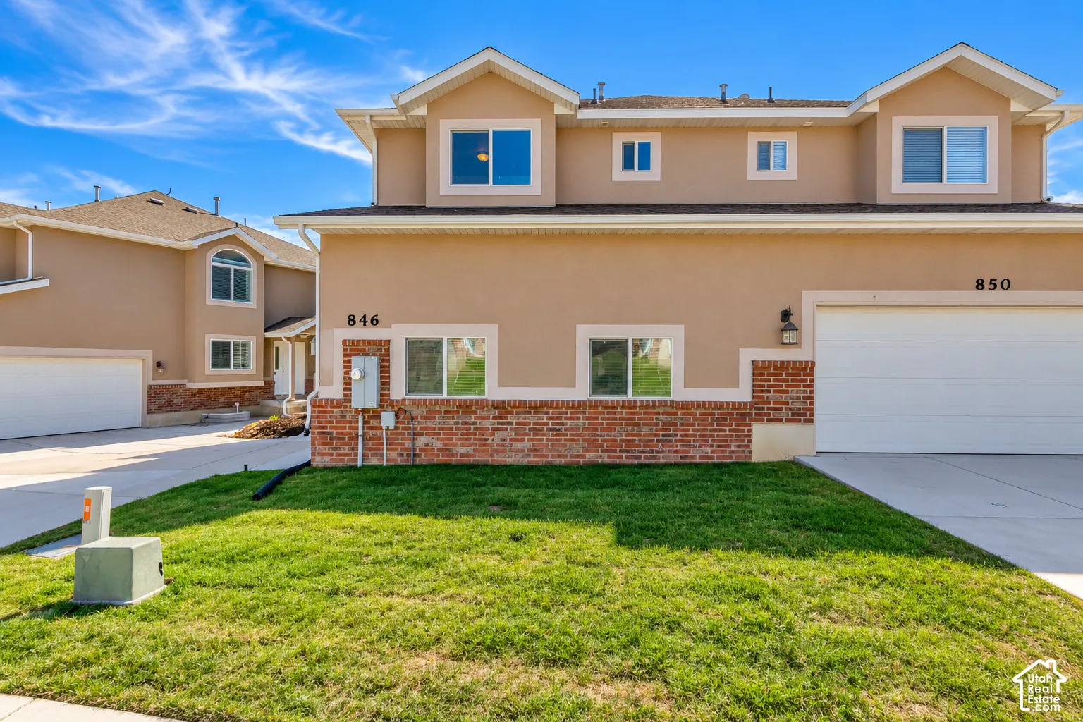 Stucco exterior with brick accents, attached garage, and multiple windows