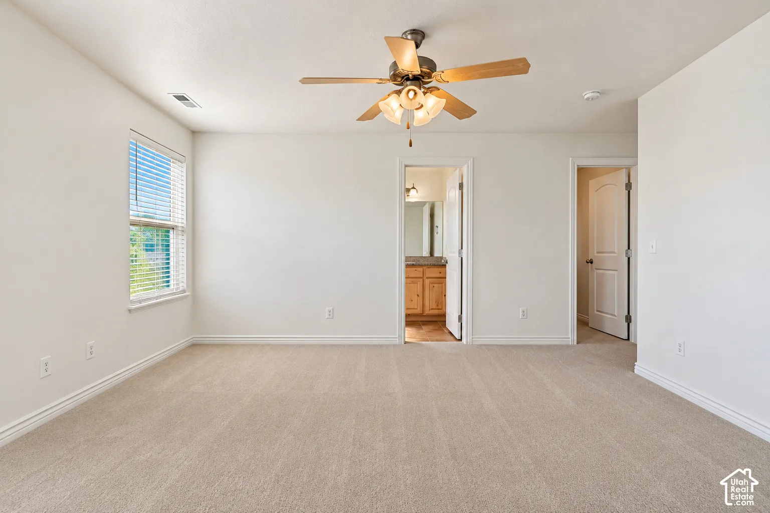 Primary Bedroom Spacious room featuring neutral carpeting, a ceiling fan with integrated lighting, and a single window with blinds- VIRTUALLY STAGED