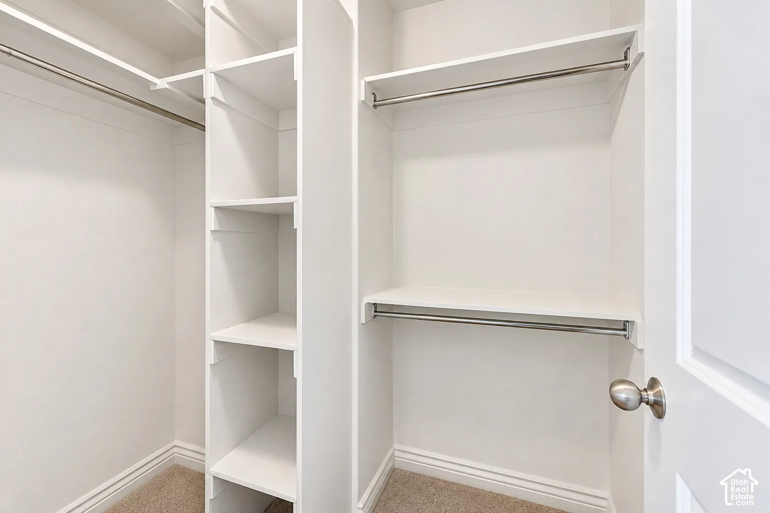Custom closet system with multiple shelving units, garment rods, and light-colored carpeting