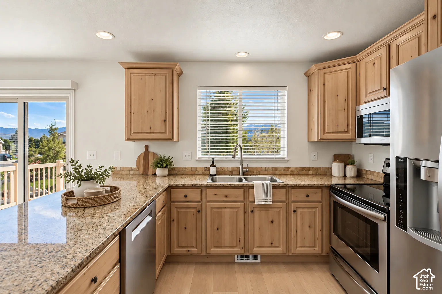 Wood cabinetry, light-toned countertops, stainless steel appliances, and wood-finish flooring- VIRTUALLY STAGED