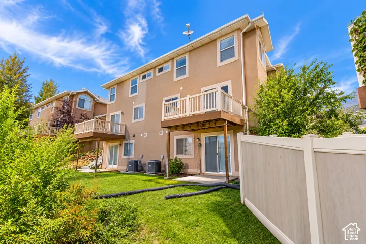 Multi-level exterior with stucco finish, wood-tone decks with white railings, and a private yard
