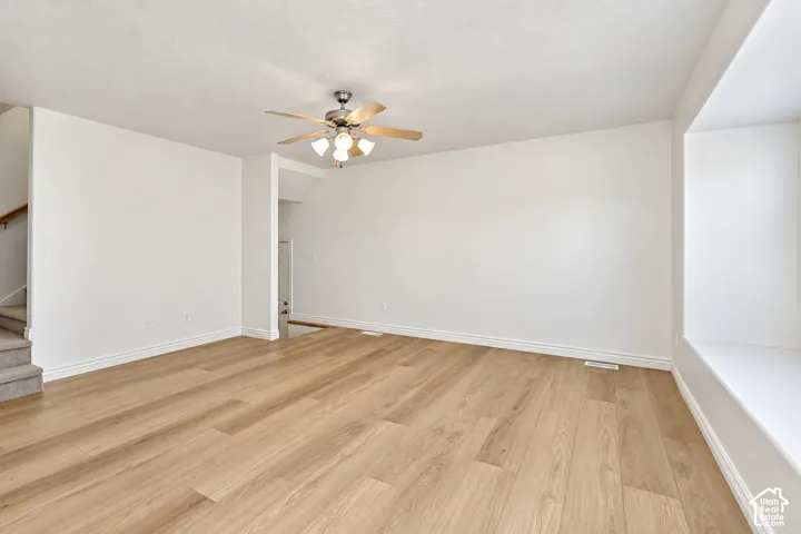 Wood-finish flooring, ceiling fan with integrated lighting, window seat with a sills, white baseboards, and neutral wall tones