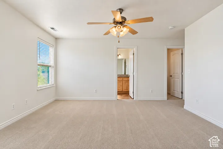 Primary Bedroom Spacious room featuring neutral carpeting, a ceiling fan with integrated lighting, and a single window with blinds- VIRTUALLY STAGED