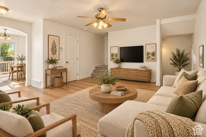 Open-concept living area with wood-finish flooring, a ceiling fan with integrated lighting, and direct access to an outdoor dining space- VIRTUALLY STAGED