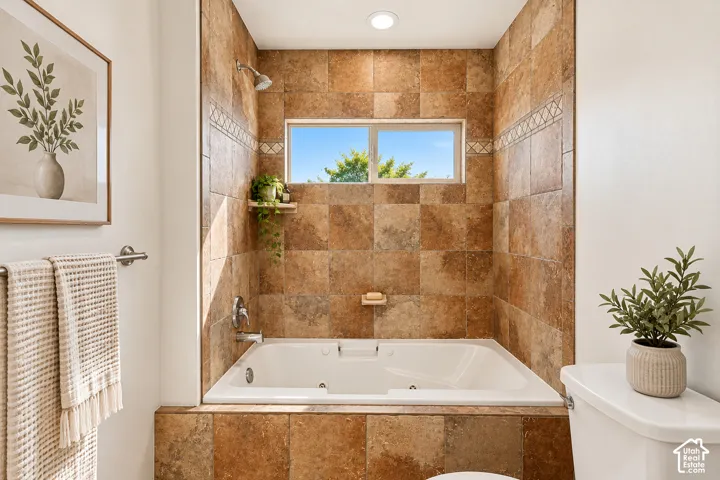 Tiled tub and shower surround with an accent border, jetted soaking tub, and an inset window- VIRTUALLY STAGED