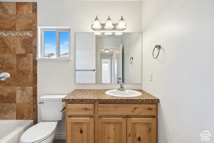 Vanity with a laminate countertop, a single sink, and wood-finish cabinetry