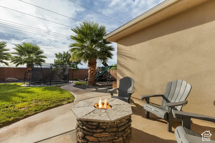 Stucco exterior with a concrete patio featuring a stacked stone fire pit and a curved concrete pathway