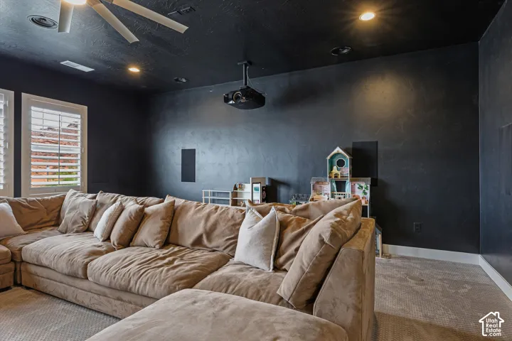 Recessed lighting, ceiling-mounted projector, ceiling fan, white plantation shutters, and textured dark walls