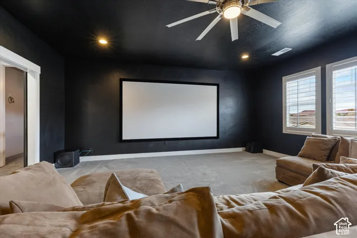Dedicated media room featuring a large projector screen, recessed lighting, and a ceiling fan