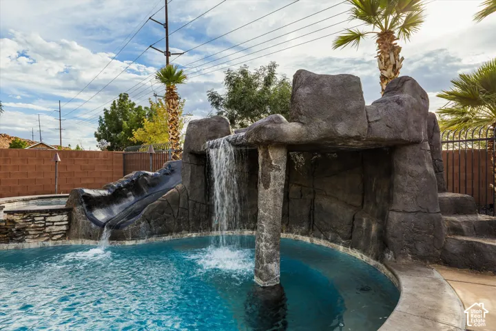 Outdoor pool with rock-finish waterfall, integrated slide, and rock-finish steps