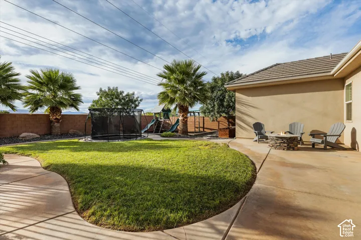 Expansive backyard featuring a curved concrete patio, a stone-clad fire pit, and a manicured lawn