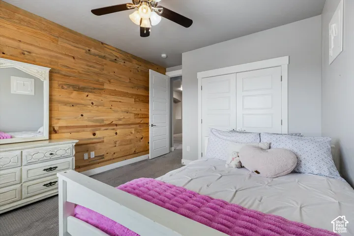 Accent wall featuring wood paneling, gray carpet, white interior door, and white bi-fold closet doors