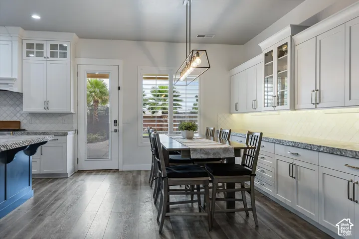 White shaker cabinetry, wood-finish flooring, full-light door, and a linear pendant light fixture