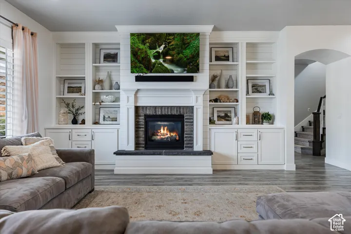 Fireplace with a dark brick surround and hearth, flanked by built-in white shelving and cabinetry