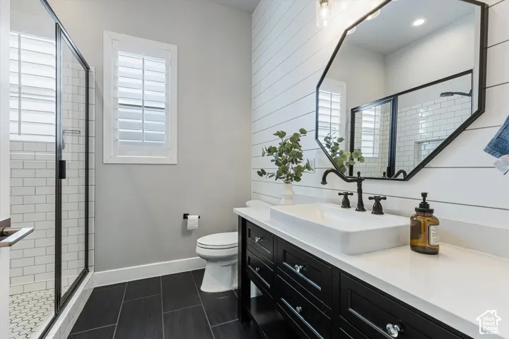 Rectangular vessel sink with dark bronze faucet, dark wood vanity with ample storage, white countertop, and shiplap accent wall