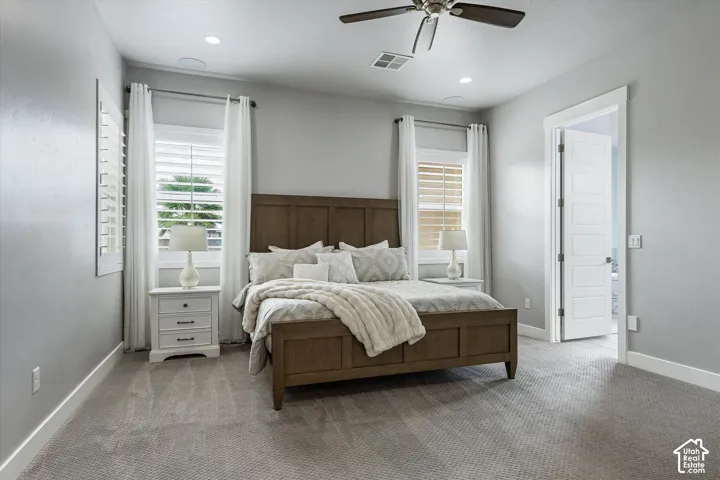 Neutral wall tones, recessed lighting, ceiling fan, carpeted flooring, and a window with plantation shutters
