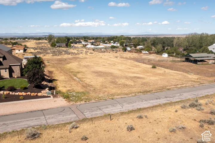 Expansive lot featuring a paved road frontage, surrounding residential properties, and distant mountain scenery