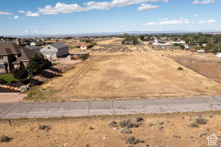 Vacant land parcel featuring a paved road frontage, natural terrain, and distant mountain scenery