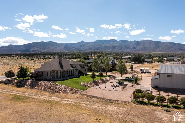 Expansive property featuring a large residence with a covered patio, manicured lawn, and a separate outbuilding