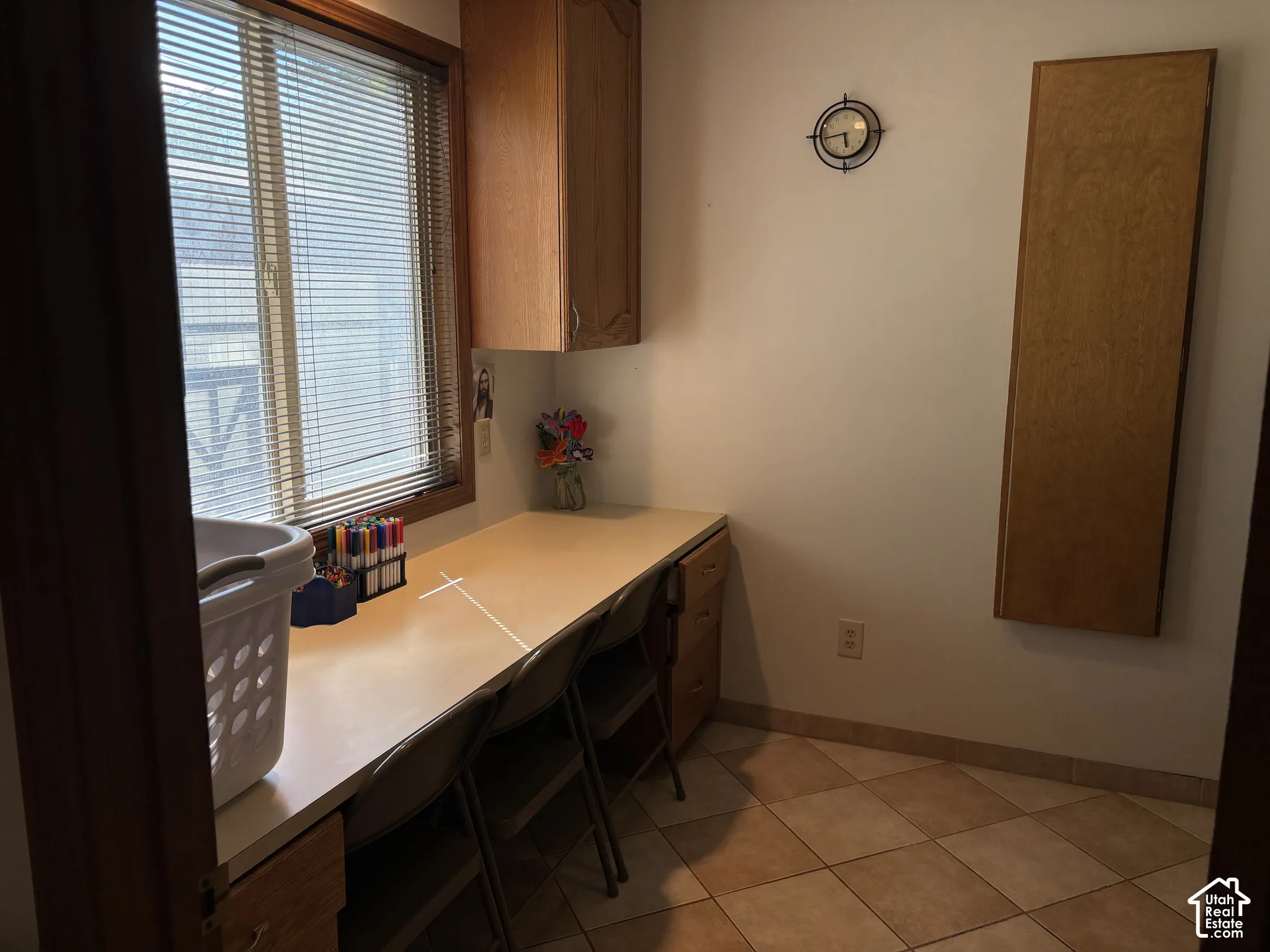 Built-in desk with overhead cabinetry, tile flooring, and a large window