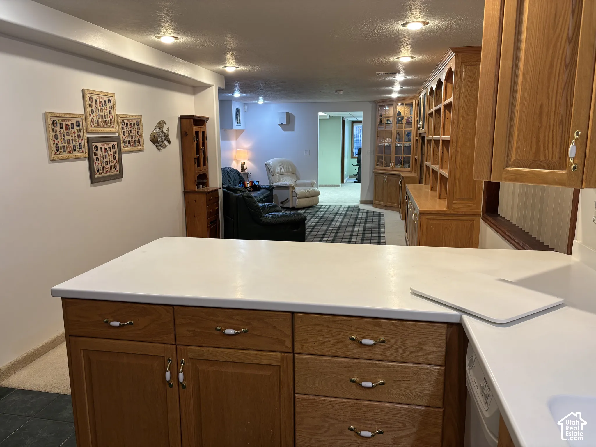 Kitchen island with solid surface countertop, recessed lighting, wood cabinetry, and integrated shelving