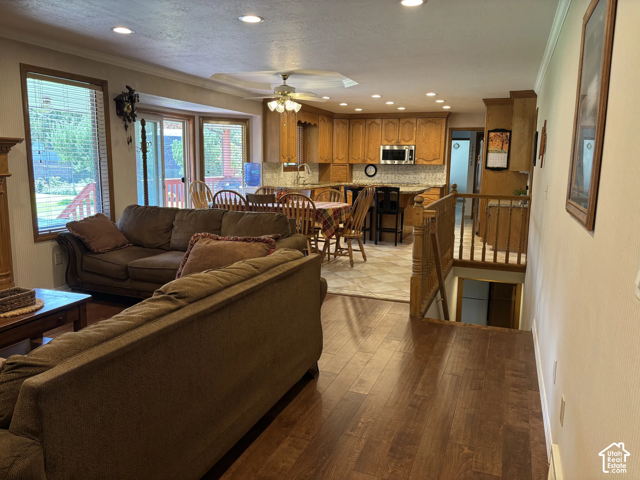 Open-concept living area with wood-finish flooring, recessed lighting, wood cabinetry, and a kitchen featuring a tile backsplash