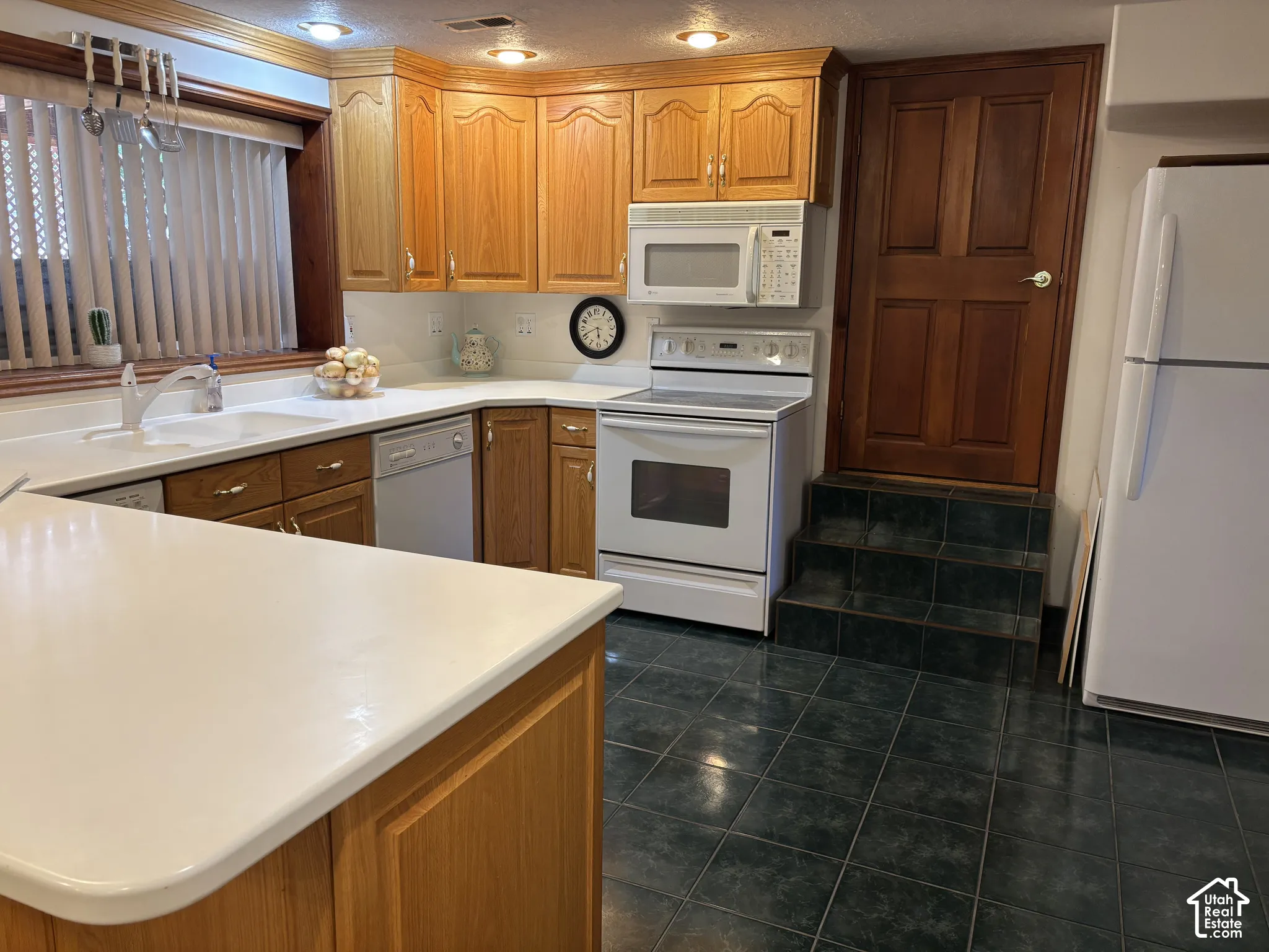 Functional kitchen featuring wood cabinetry, white countertops, a built-in dishwasher, and a white oven/stove