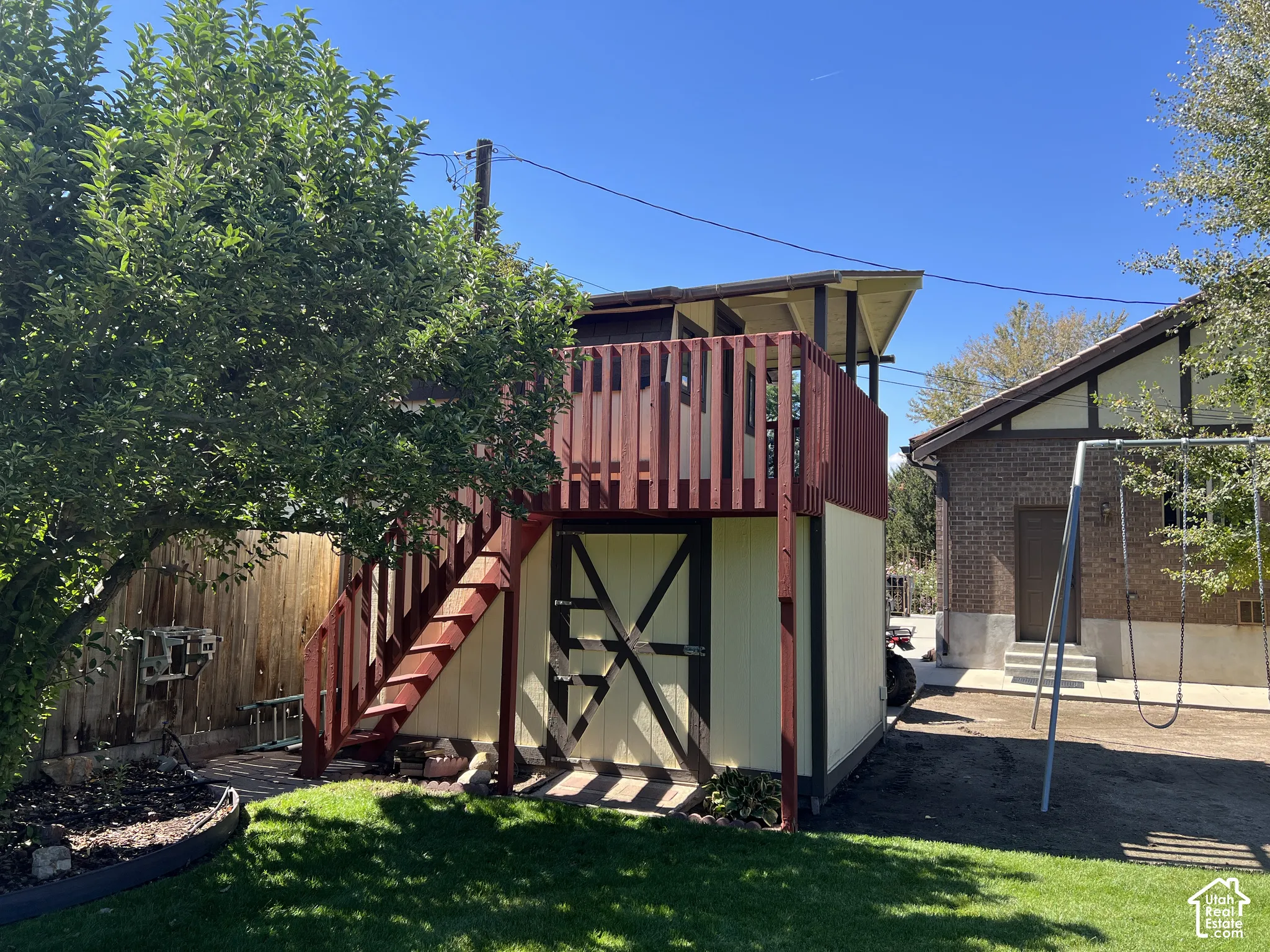 Two-story wooden play structure with exterior staircase and upper-level railing