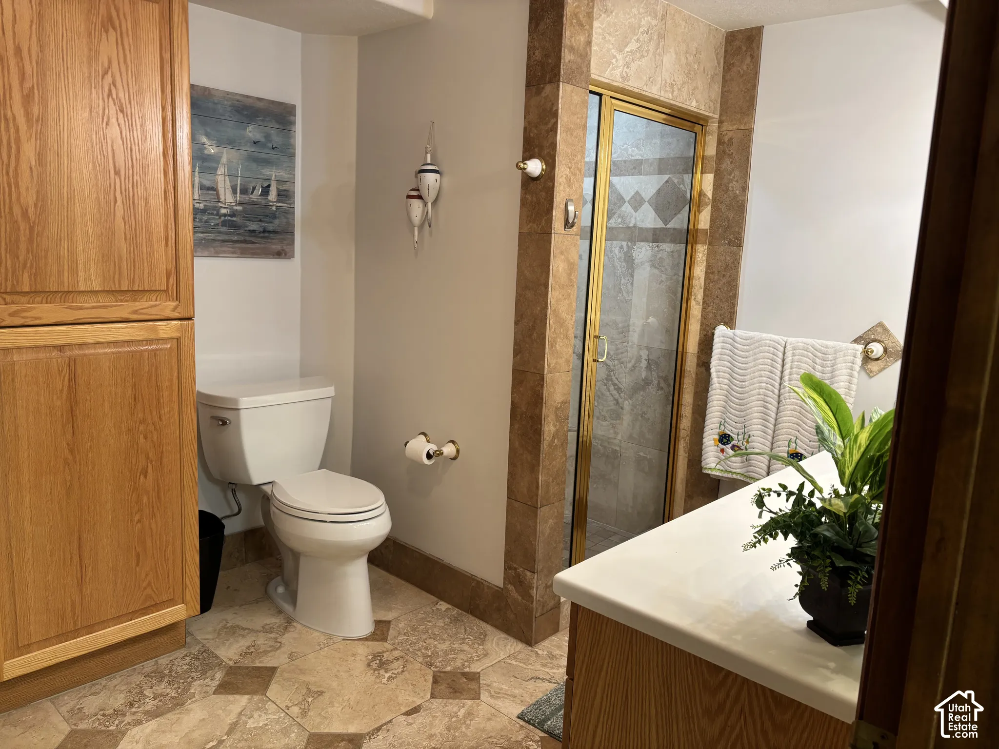 Wood-finish cabinetry, tile flooring with geometric accents, and a shower with a framed glass enclosure