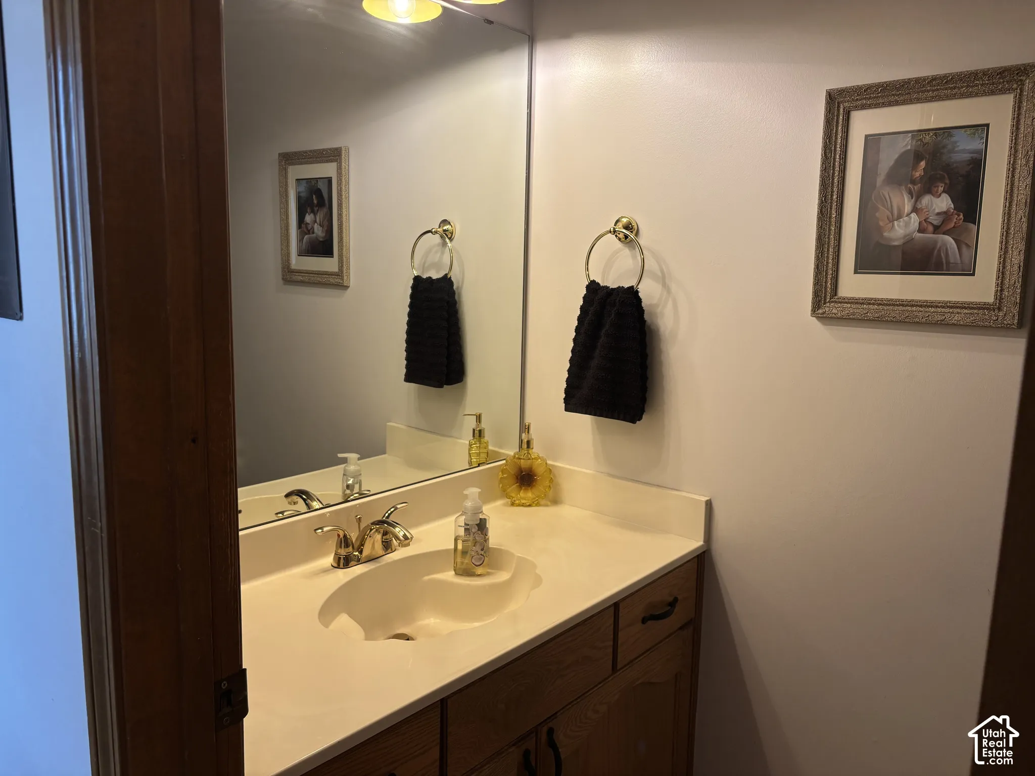 Vanity with an integrated sink, polished chrome faucet, wood-finish cabinetry, and overhead illumination