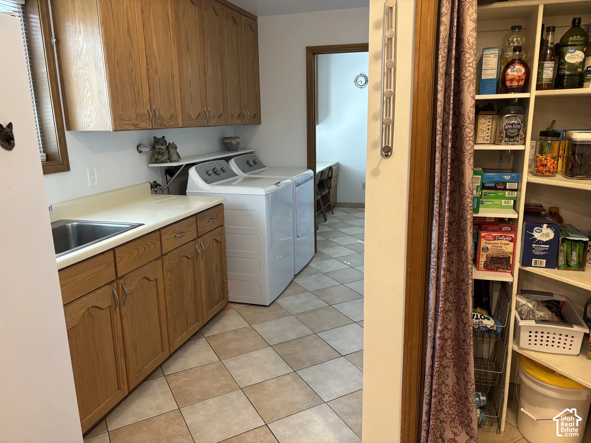 Utility area featuring wood-finish cabinetry, a stainless steel sink, and a checkered tile floor
