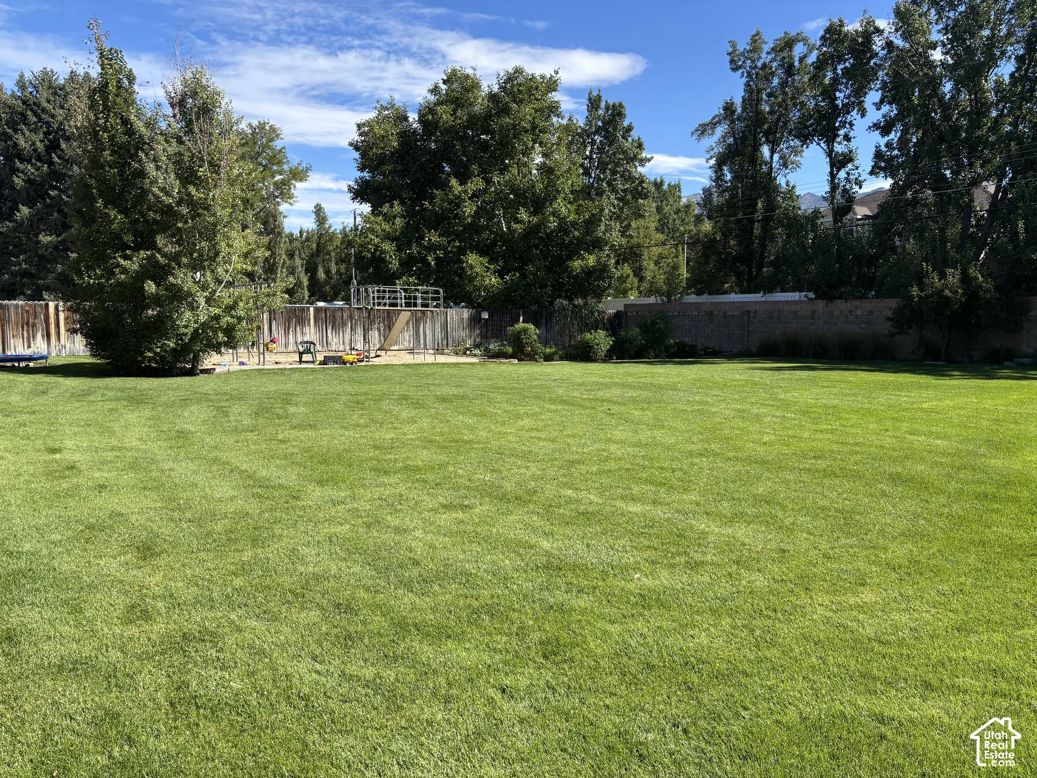 Expansive grassy yard with mature trees and wood fencing
