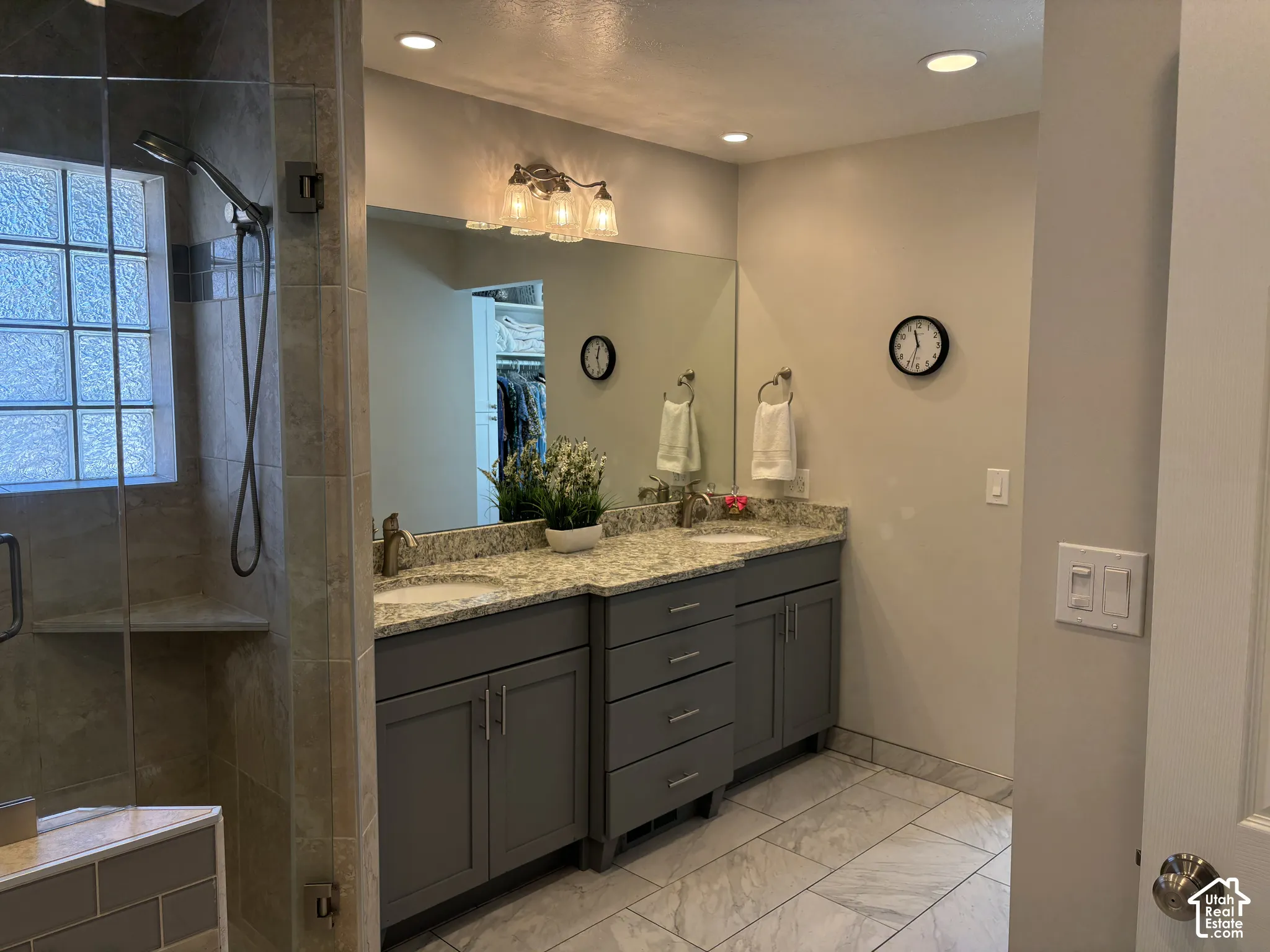 Dual vanity with gray cabinetry and stone countertops