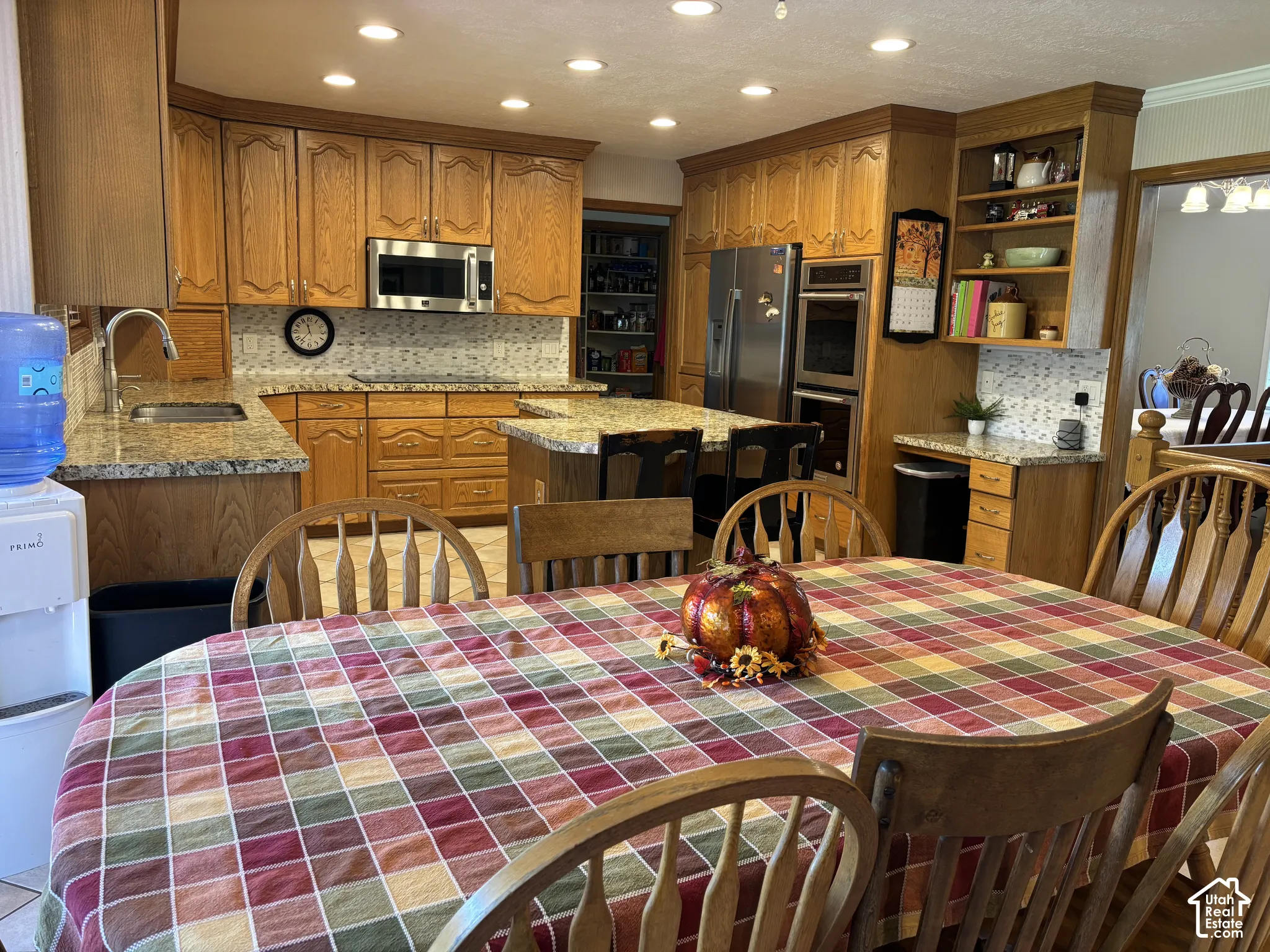 Kitchen featuring wood cabinetry, granite countertops, stainless steel appliances, a center island with seating, and recessed lighting