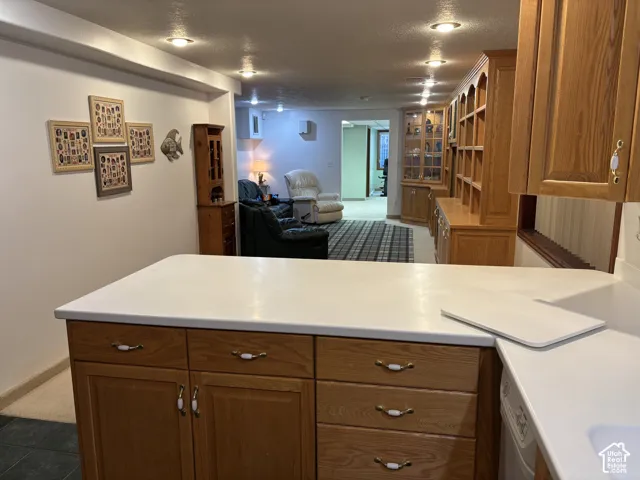 Kitchen island with solid surface countertop, recessed lighting, wood cabinetry, and integrated shelving
