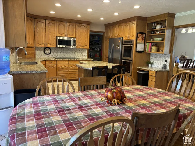 Kitchen featuring wood cabinetry, granite countertops, stainless steel appliances, a center island with seating, and recessed lighting