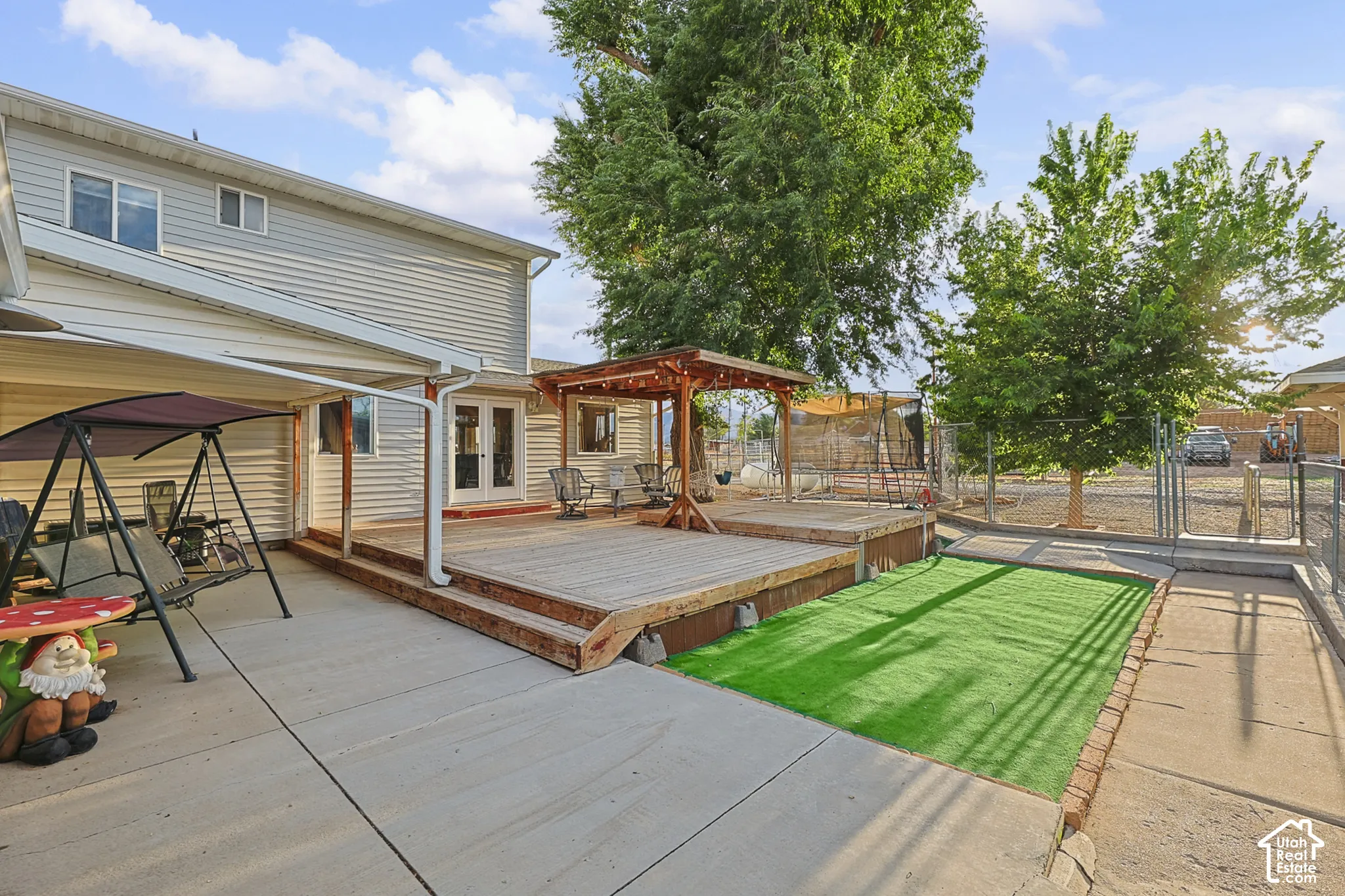 Expansive wood-finish deck with built-in pergola, concrete patio, and artificial turf area