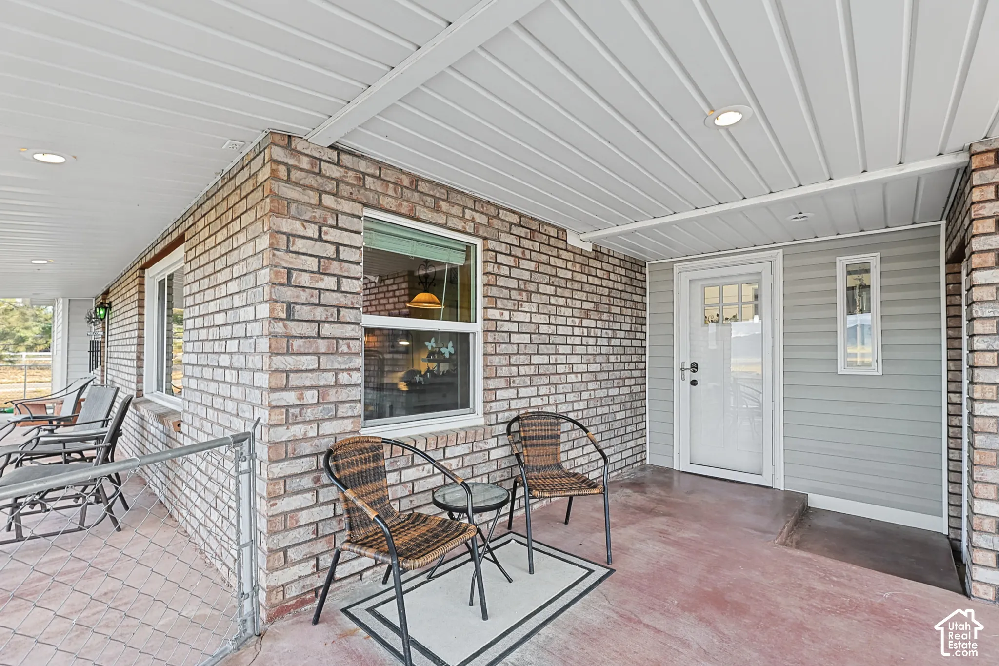 Brick exterior with a covered porch, recessed lighting, and a white entry door with a privacy screen
