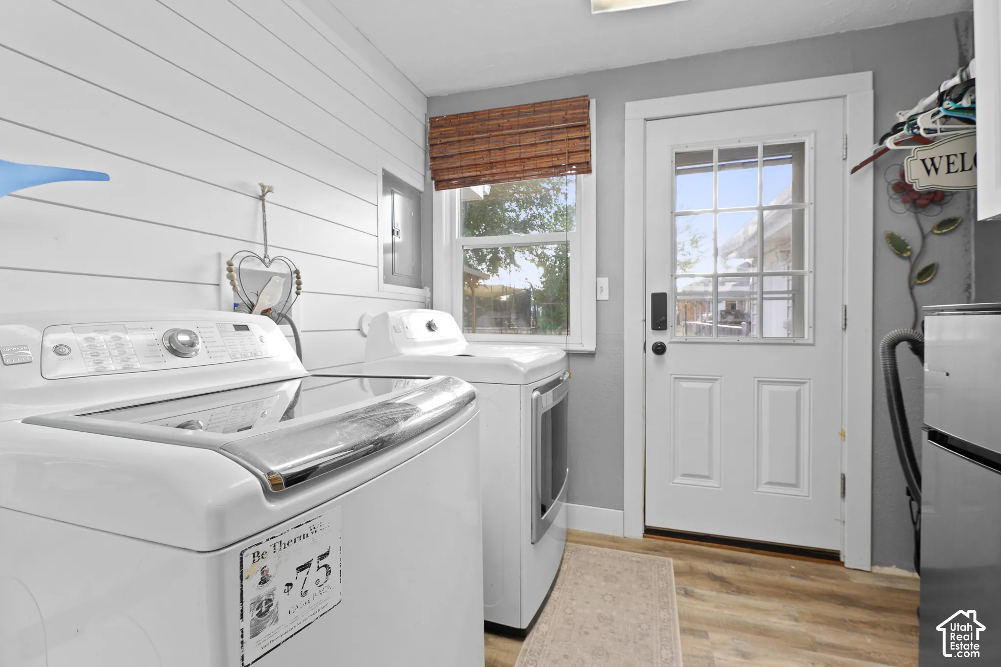Wood-finish flooring with white baseboards, a rear exterior door with glass panes, and a window with a woven blind