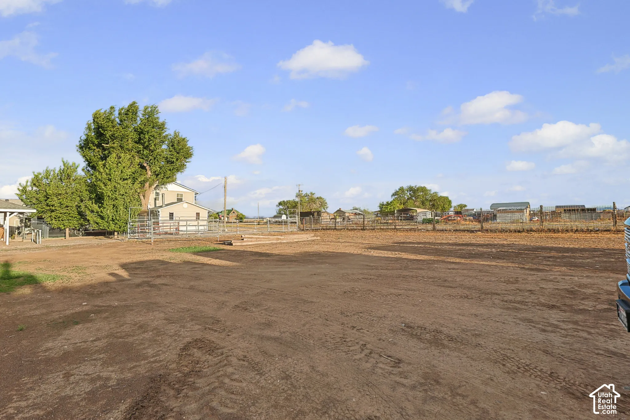 Expansive property featuring a two-story residence, mature trees, and perimeter fencing