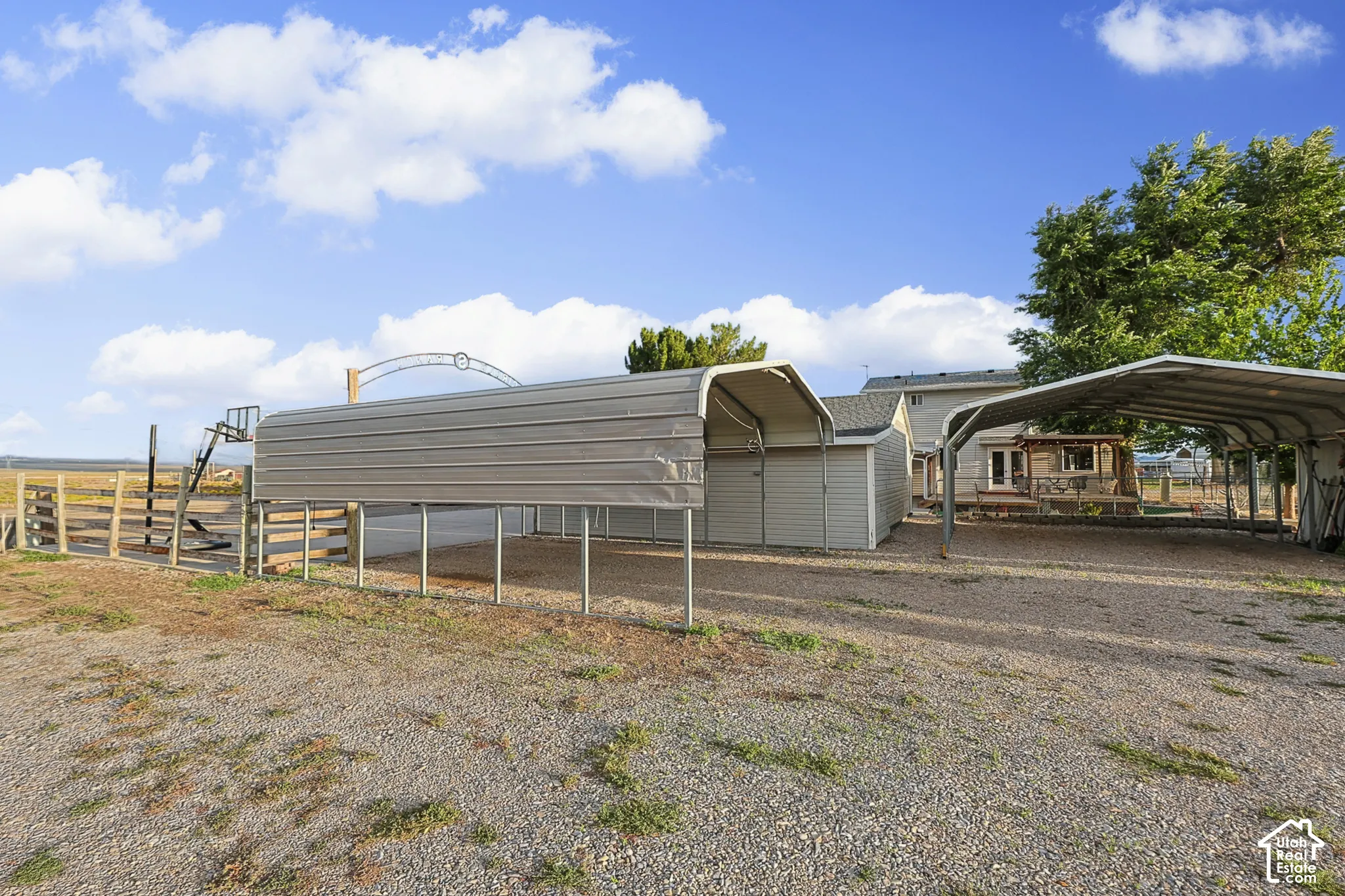 Gravel driveway with multiple covered carports and a separate storage shed