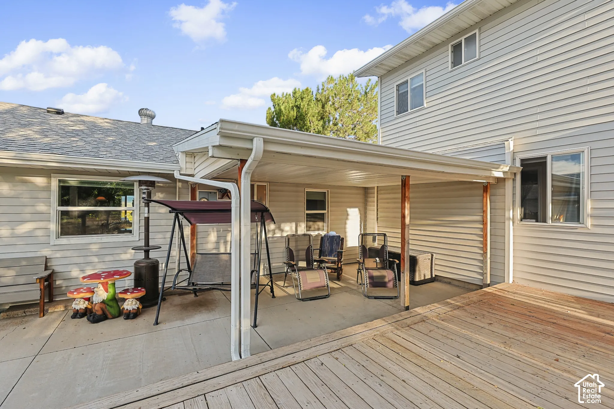 Expansive outdoor living area featuring a wood deck, concrete patio, and a covered patio structure