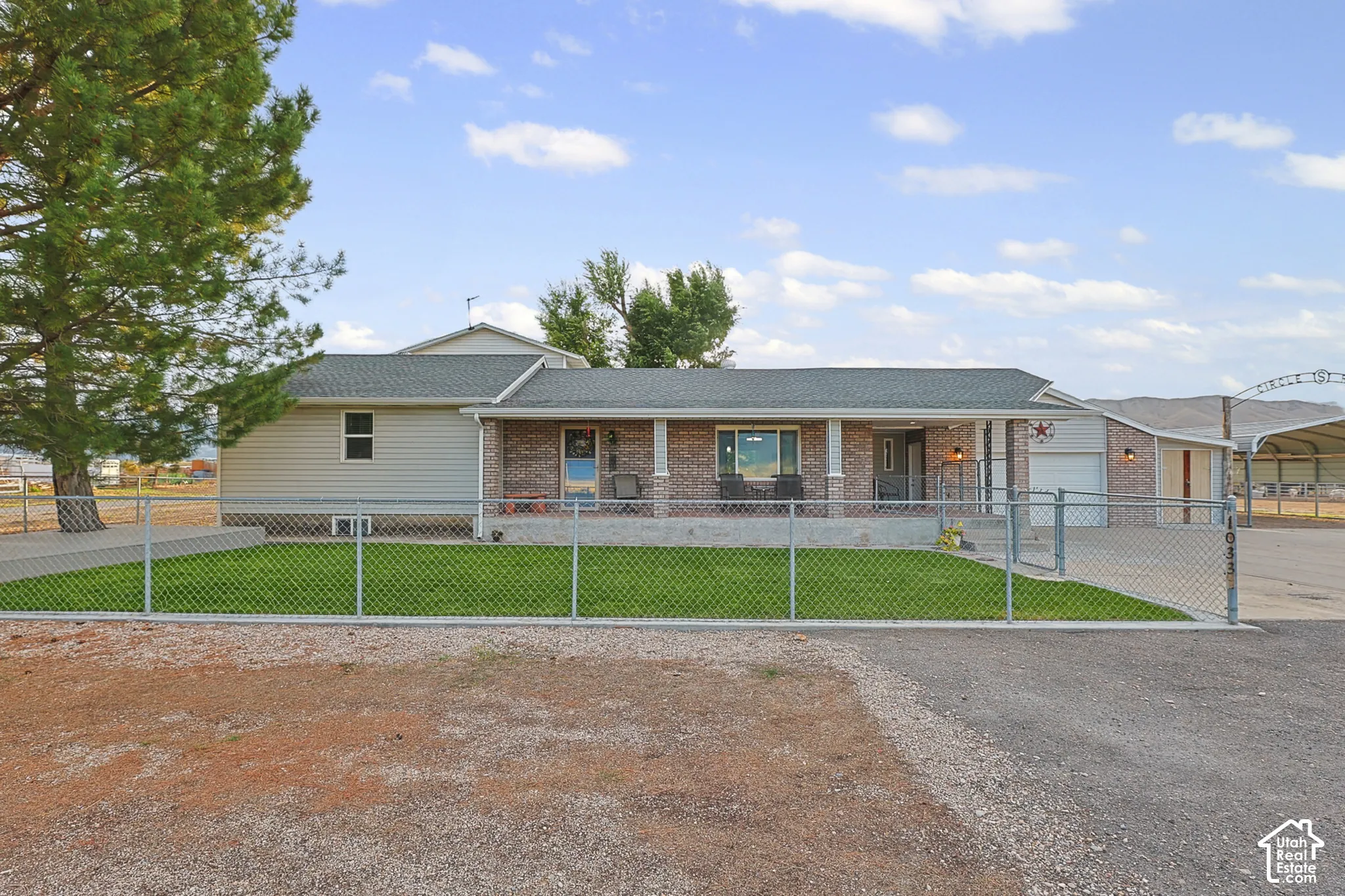 Brick and siding exterior with a covered front porch, attached garage, and a chain-link fence enclosing a front lawn