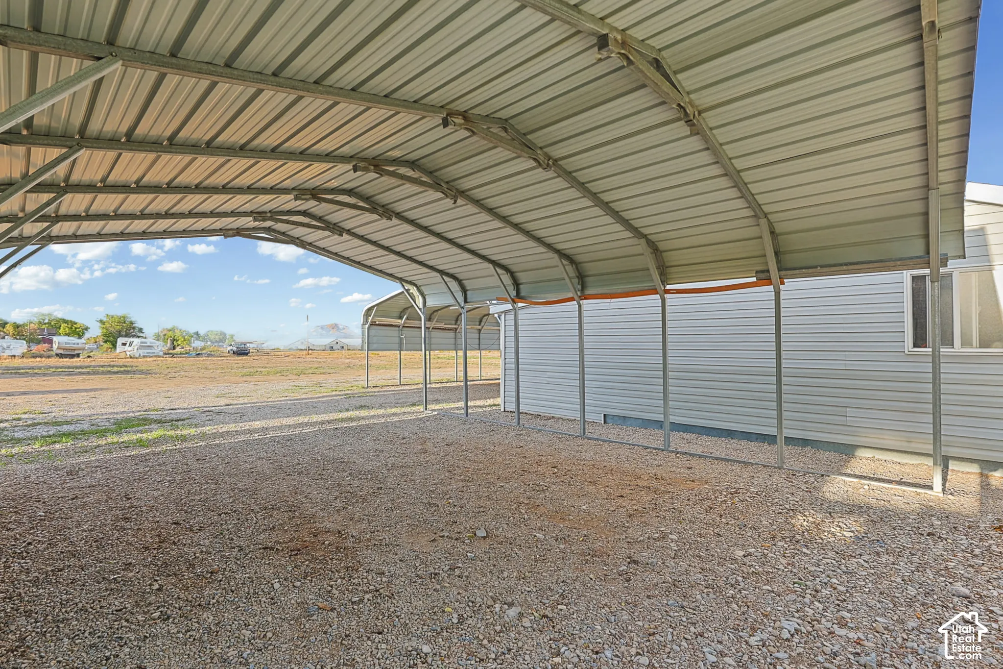 Large metal carport structure with a gravel surface