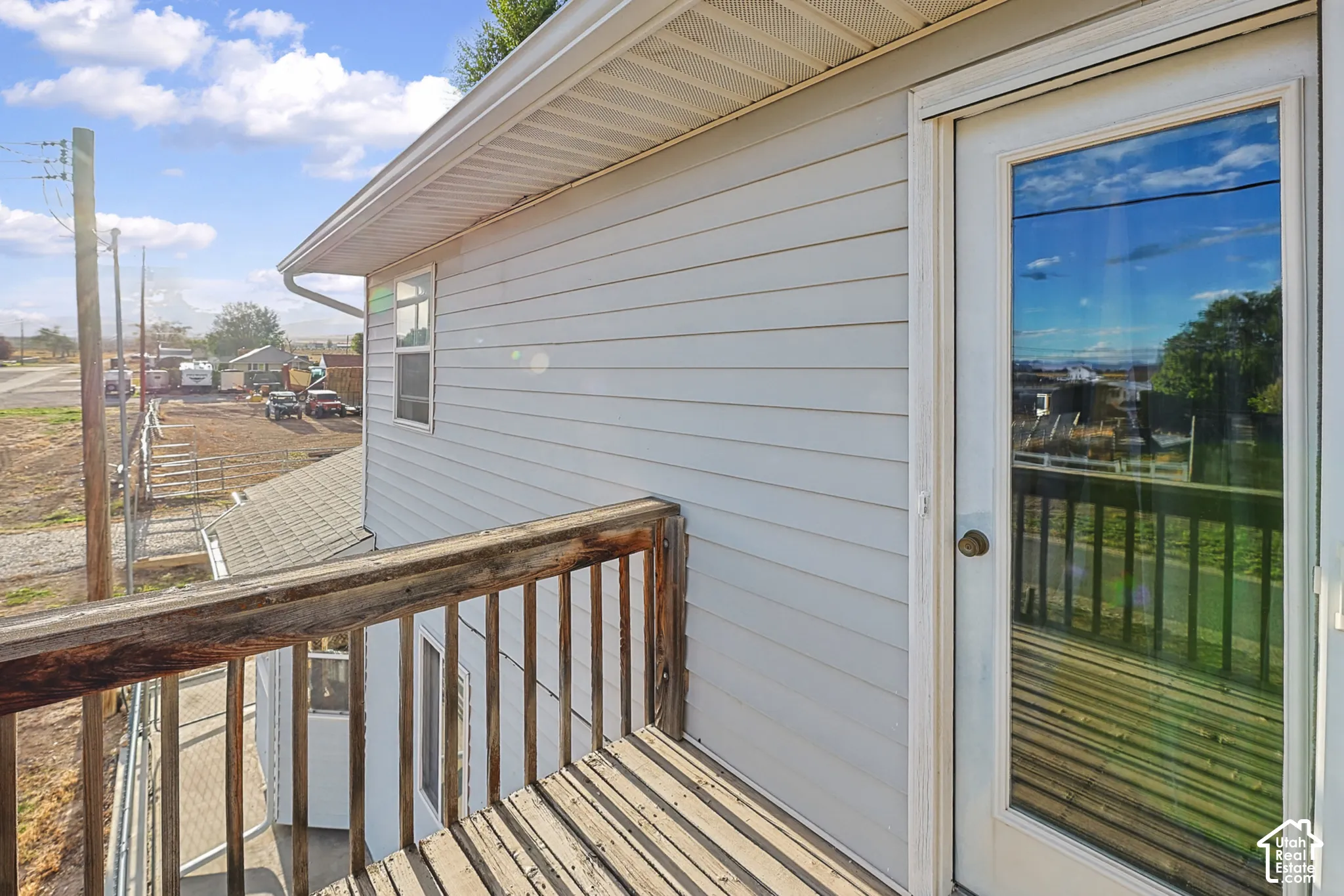 White siding exterior with a wood deck, wood railing, and a glass-paneled exterior door