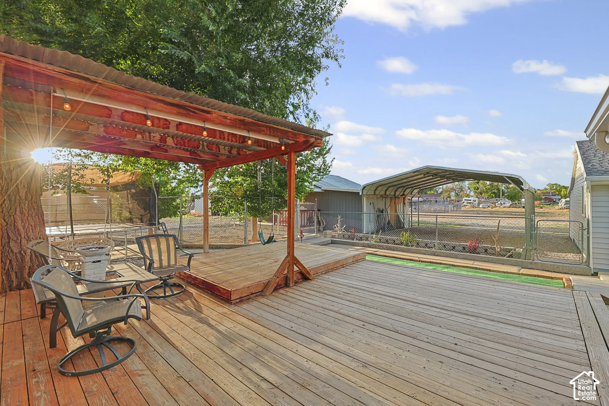 Expansive wood-finish deck with a built-in pergola, outdoor string lighting, and an additional sheltered structure