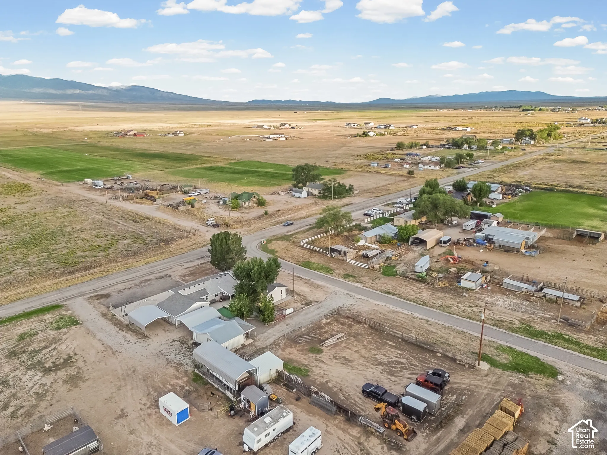 Extensive acreage with multiple structures, including a primary residence with an attached carport, additional outbuildings, and a large open field