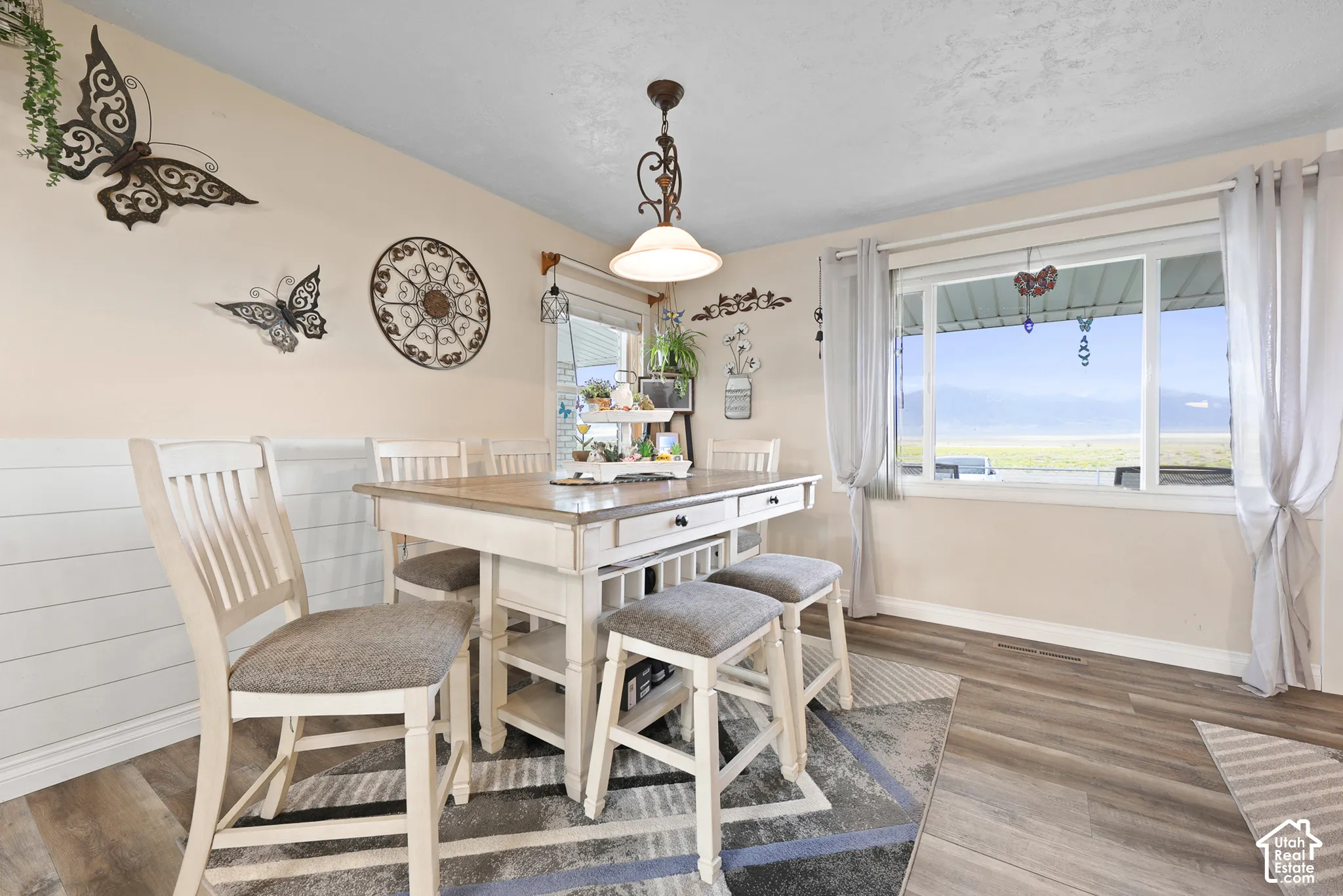 Wood-finish flooring, white shiplap wainscoting, and a large window with white trim